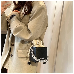 Detail of black cube handbag with beige drawstring inner bag and chunky silver chain link