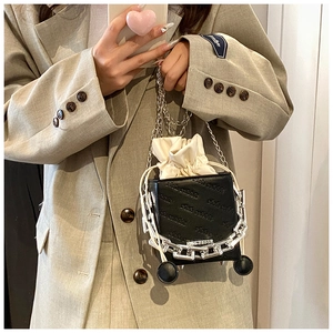 Detail of black textured leather bag with metallic chain and white drawstring inner bag