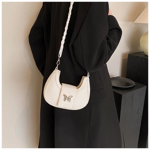 Detail of white crescent bag with silver butterfly buckle and woven shoulder strap