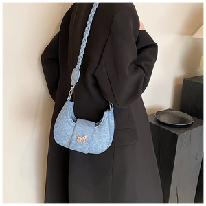 Blue denim texture hobo bag with a woven strap and gold butterfly buckle on a black coat