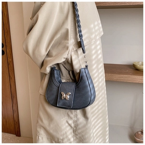 Detail of black hobo bag with gold butterfly buckle and woven strap on model