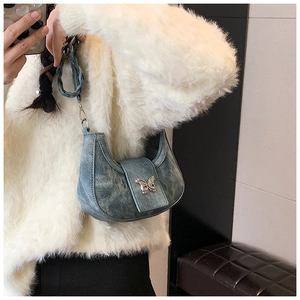 Detail of blue crescent bag featuring a silver butterfly buckle and woven shoulder strap