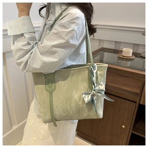 Close-up of light green tote bag with wrinkled texture and fashion scarf decoration