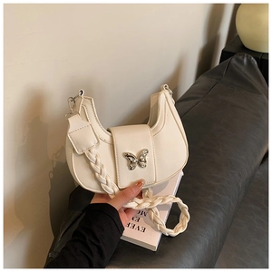 Close-up of a white crescent moon bag with a silver butterfly buckle and woven strap