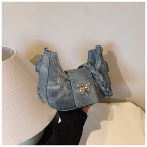 Detail of denim crescent bag with woven handle and silver butterfly buckle closure