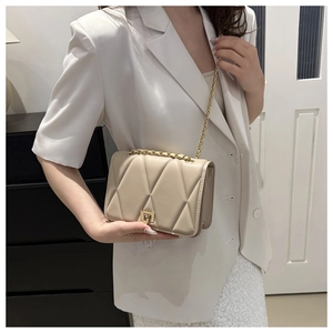 Dettaglio borsa trapuntata beige con catena dorata su modella con un blazer