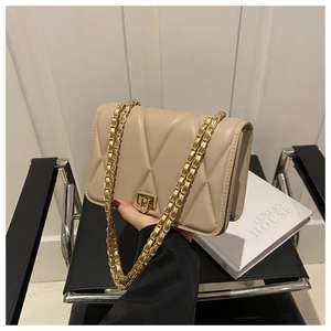 Dettaglio della borsa a tracolla beige trapuntata con catena dorata e chiusura a scatto