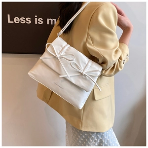 Detail of white quilted puffy shoulder bag featuring two decorative 3D bow knots