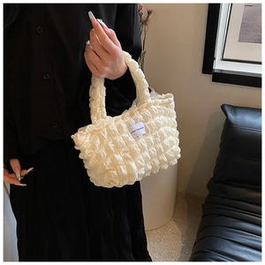 Detalle de la textura de tela popcorn blanca y etiqueta Love Fashion en el bolso de hombro pequeño