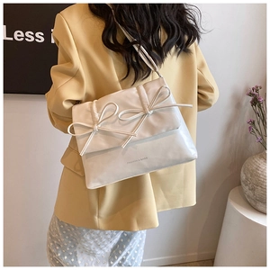 Detail of white PU leather crossbody bag with stylish bow accents and adjustable strap