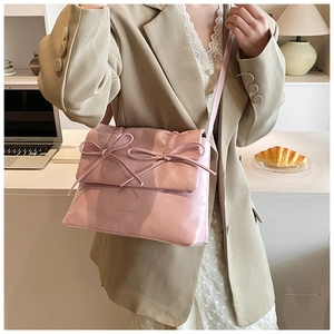 Detail of pink leather crossbody bag featuring twin bows and Fashion & Bags text logo