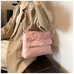 Close-up of pink bow-knot detail and pleated texture on a stylish leather shoulder bag