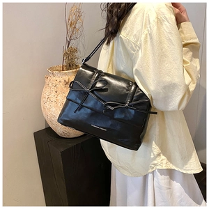 Detail of black faux leather handbag with ribbon bows and Fashion & Bags text logo