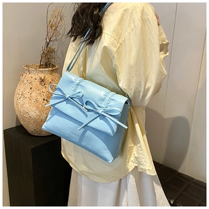Close-up of light blue shoulder bag with decorative bows and ruffled edge details