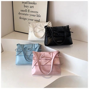 Detail of multi-color bow tote bags in black, white, blue and pink on display stand