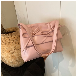 Close-up of pink PU leather bag with elegant bow detail and pleated texture surface