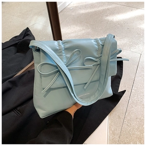 Close-up of sky blue quilted puffer bag with bow detail and brand lettering