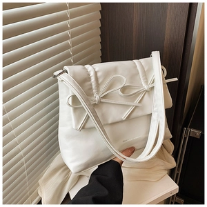 Detail of white quilted tote bag with bow accent and natural sunlight window shadow