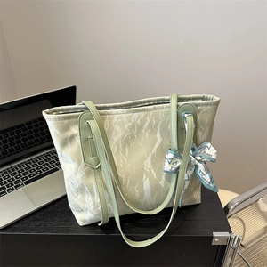 Light green large tote bag with marble texture, silk scarf decoration and laptop on desk