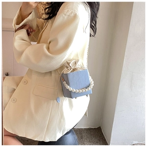 Détail du sac seau bleu clair avec grande poignée en perles et doublure en satin