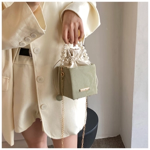 Vue détaillée du sac boîte vert clair avec poignée en perles et sac intérieur en satin