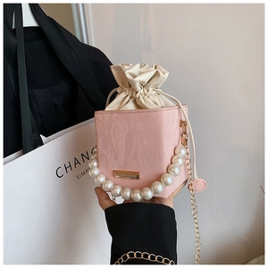 Vue détaillée d'un sac seau rose avec poignée en perles et chaîne dorée