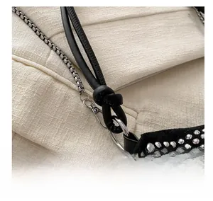Detail of black leather cord with silver square chain and metal rivets on suede surface