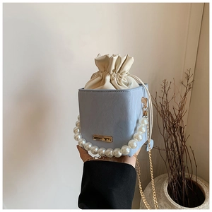 Détail du sac boîte bleu clair avec poignée en perles et bandoulière chaîne dorée