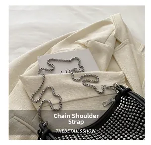 Detail of silver box chain strap on a black shoulder bag with sparkling rhinestones