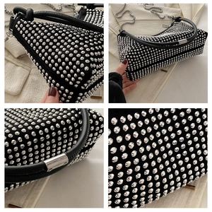 Detail of silver rivets on black suede underarm bag with leather handle and metal chain