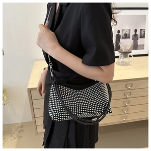 Detail of a sparkling silver rhinestone baguette bag with chain strap held by a model