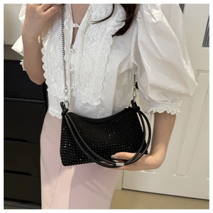 Detail of black rhinestone shoulder bag with silver chain strap worn on the body