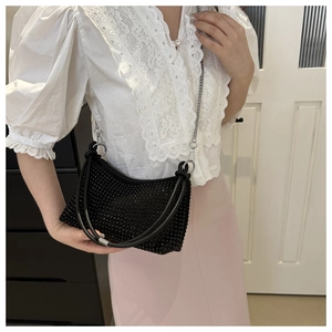 Close-up of elegant black rhinestone shoulder bag with silver chain and glossy finish