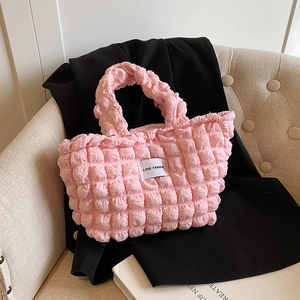Sac bandoulière chic en tissu rose bullé avec écusson LOVE FASHION sur canapé