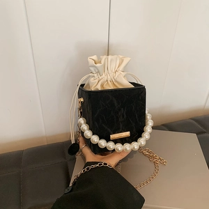 Elegant black box bag with pearl handle and gold chain, marble texture crossbody style