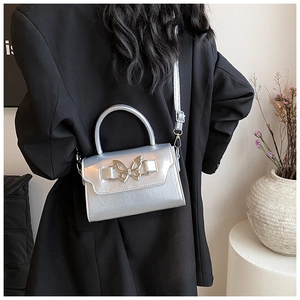 Detail of silver crossbody bag with metal butterfly clasp and sleek top handle strap