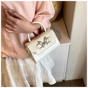 Detail of elegant cream white crossbody bag featuring a silver butterfly metal buckle