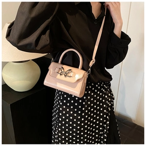 Detail of pink patent leather handbag featuring a decorative silver butterfly buckle