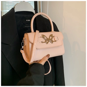 Detail of pink faux leather handbag featuring a golden butterfly buckle and top handle