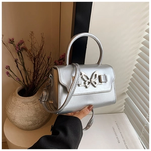Macro detail of silver PU leather handbag showing lychee texture and butterfly ornament