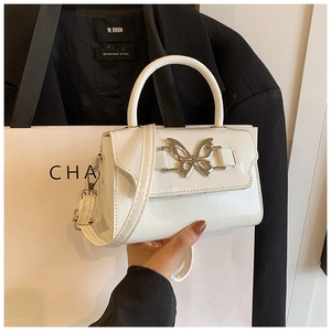 Detail of white leather handbag with silver butterfly clasp held against a blazer