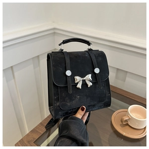 Close-up of vintage black square bucket bag with silver bow ornament and top handle