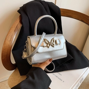 Metallic silver crossbody bag with golden butterfly buckle and textured finish