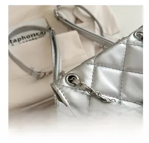 Detail of silver quilted backpack showing metallic eyelets and chain strap design