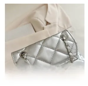 Detail of silver quilted texture and metallic chain strap on a stylish small backpack