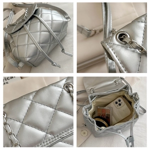 Detail view of silver quilted backpack showing chain trim, leather texture and inner storage