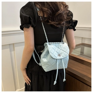 Detail of light blue quilted mini backpack with silver chain strap and metal turn-lock