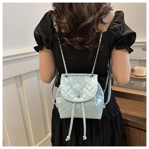 Detail of light blue quilted backpack featuring silver twist lock and chain straps