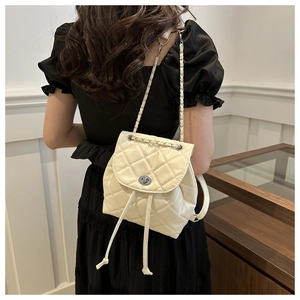 Detail of a creamy white quilted mini backpack with silver metal lock and chain straps