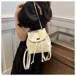 Close-up of beige quilted chain backpack featuring silver twist lock and drawstring detail
